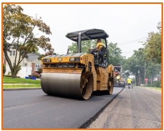 A man is driving a roller on a road.