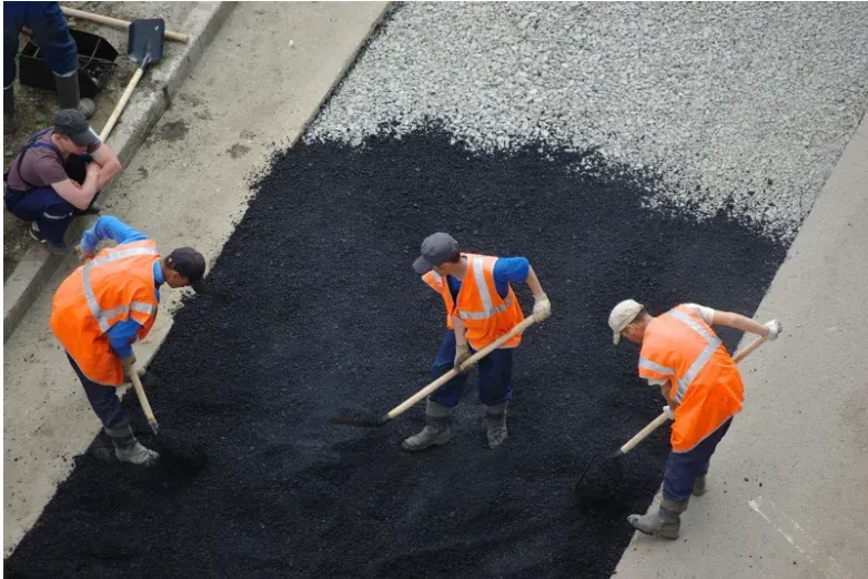 A group of construction workers are working on a road