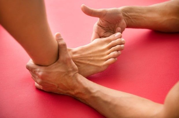 Person holding a woman's foot and examining them. 
