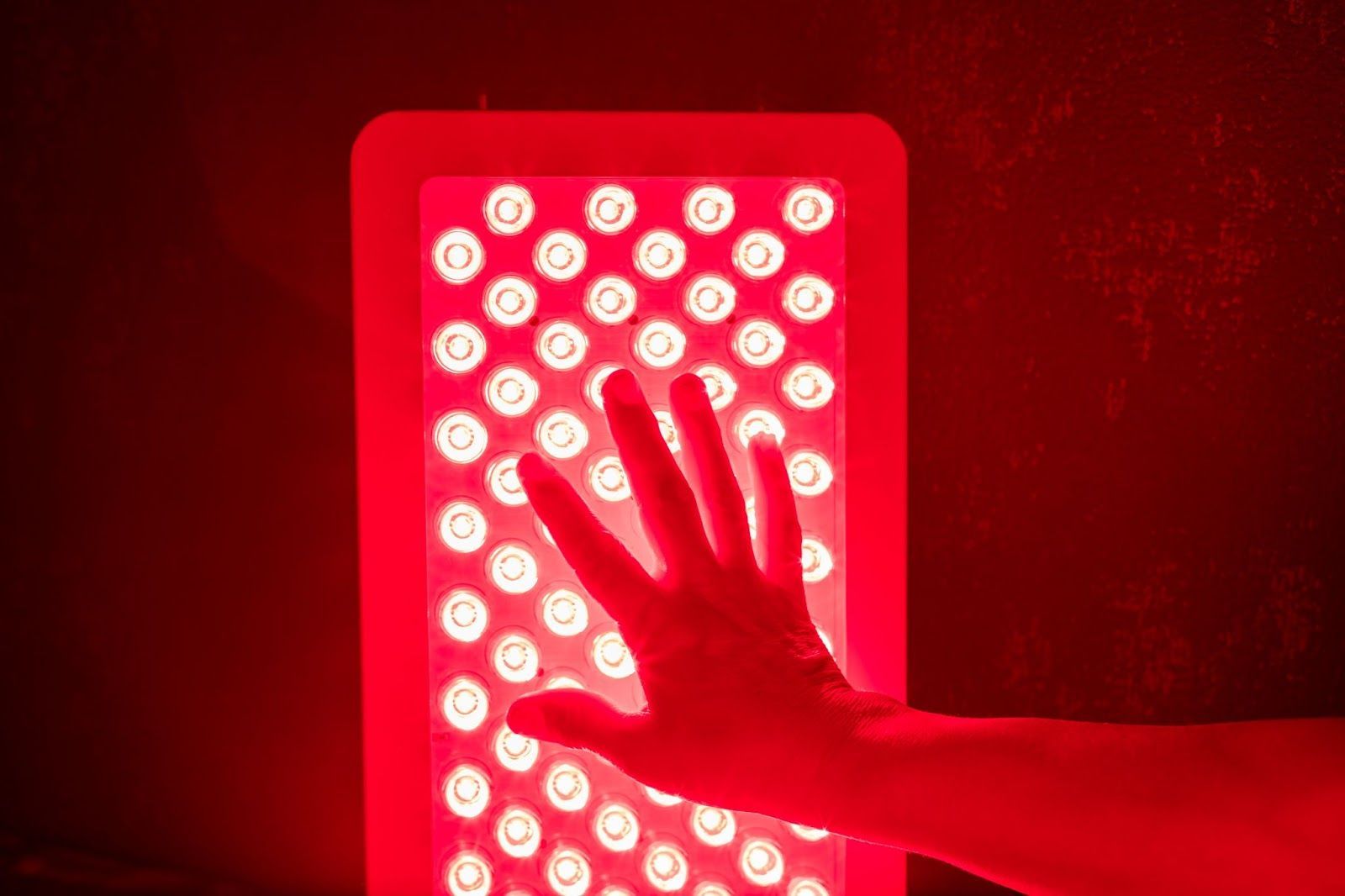 Person touching a red light therapy panel. 