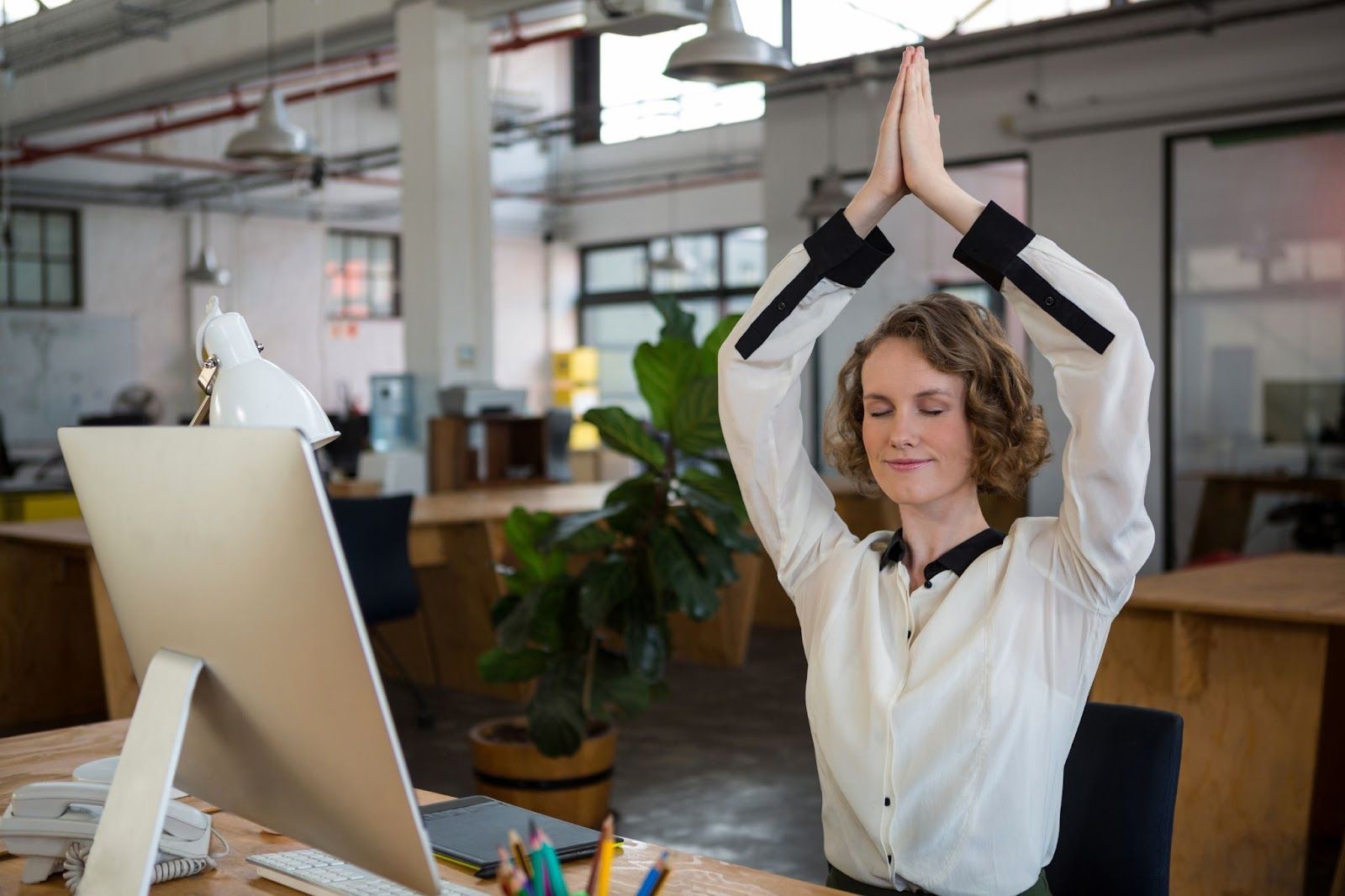 A woman is performing yoga while on her break in the office.