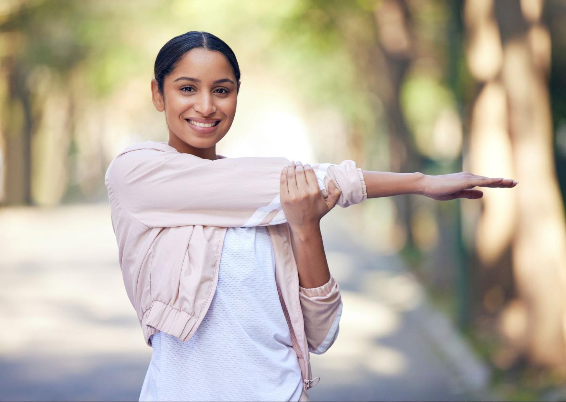 Woman smiling and stretching her arm across her chest. 