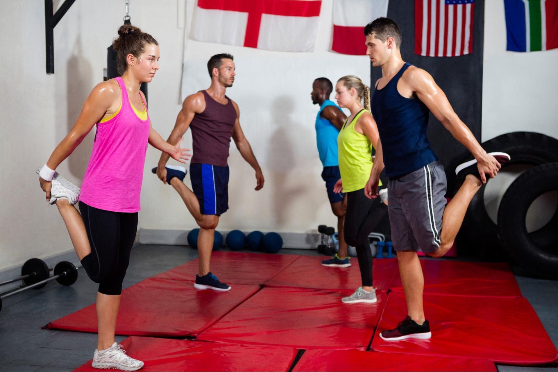 A group of people stretches their legs in a gym.