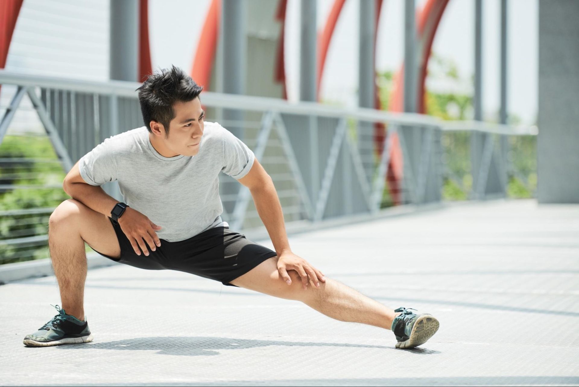 Man in athletic wear stretching his legs on a bridge. 