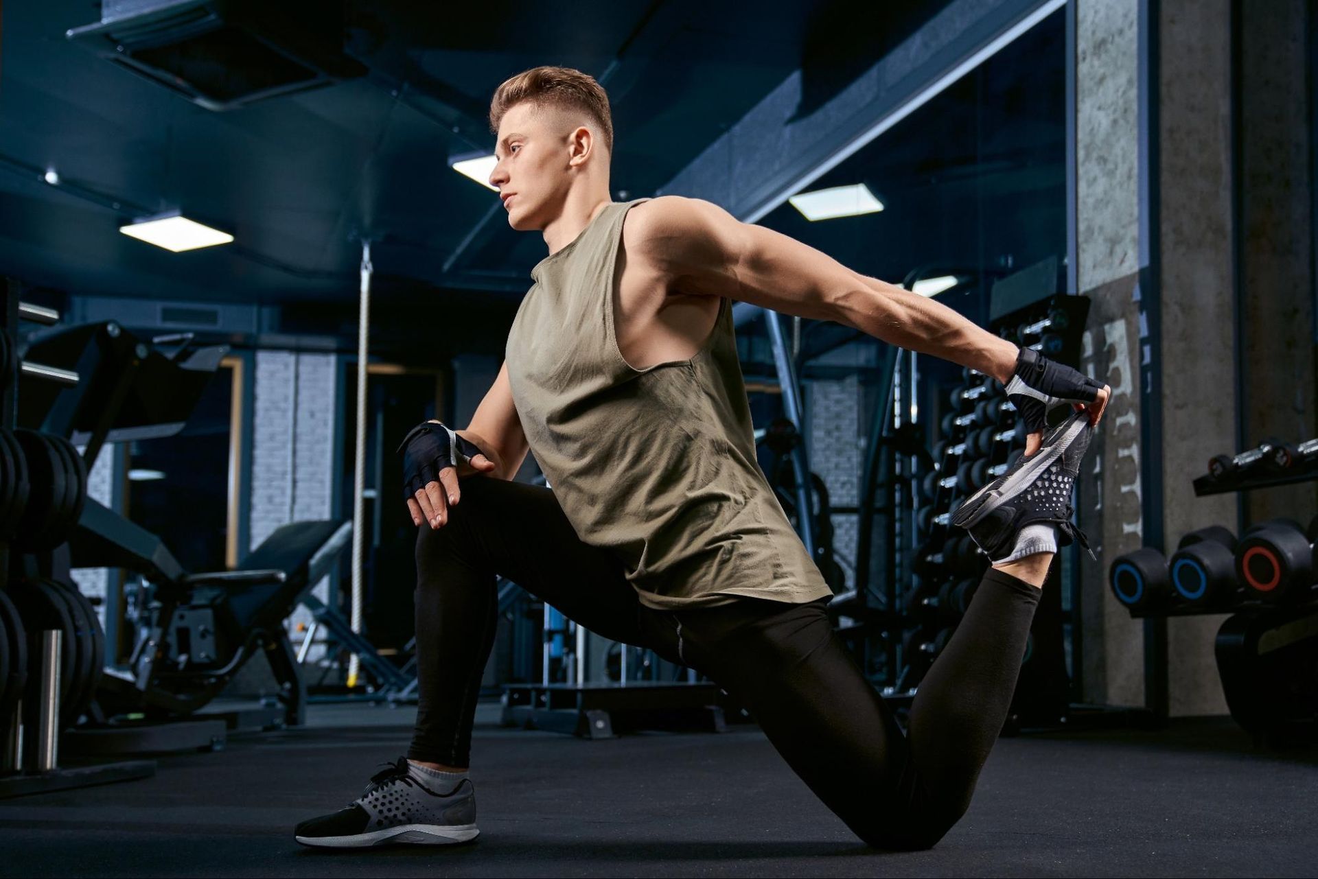 A man stretches his legs in a gym.