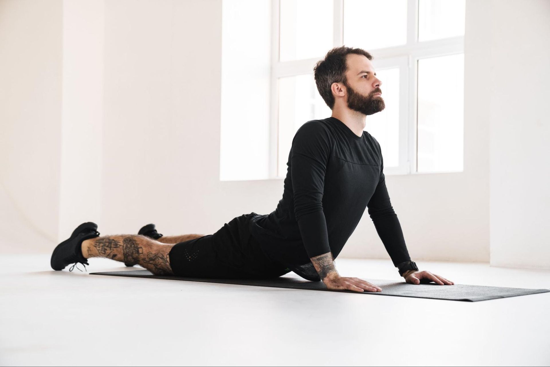 A man stretches on a yoga mat in his home.