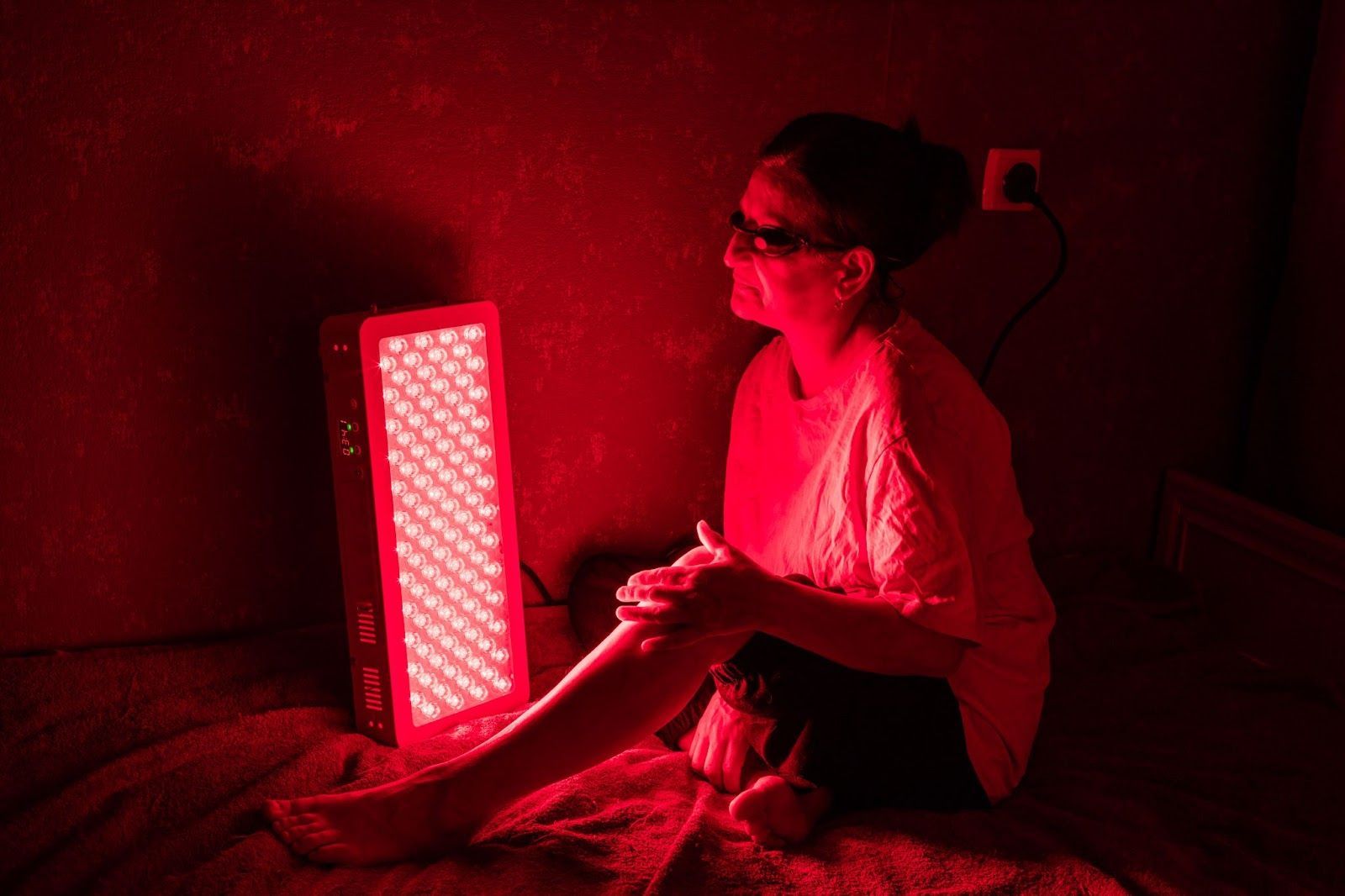 An older woman is under treatment for red light therapy. 