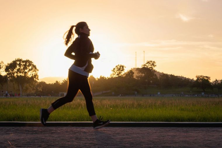Woman running outdoors at sunset.
