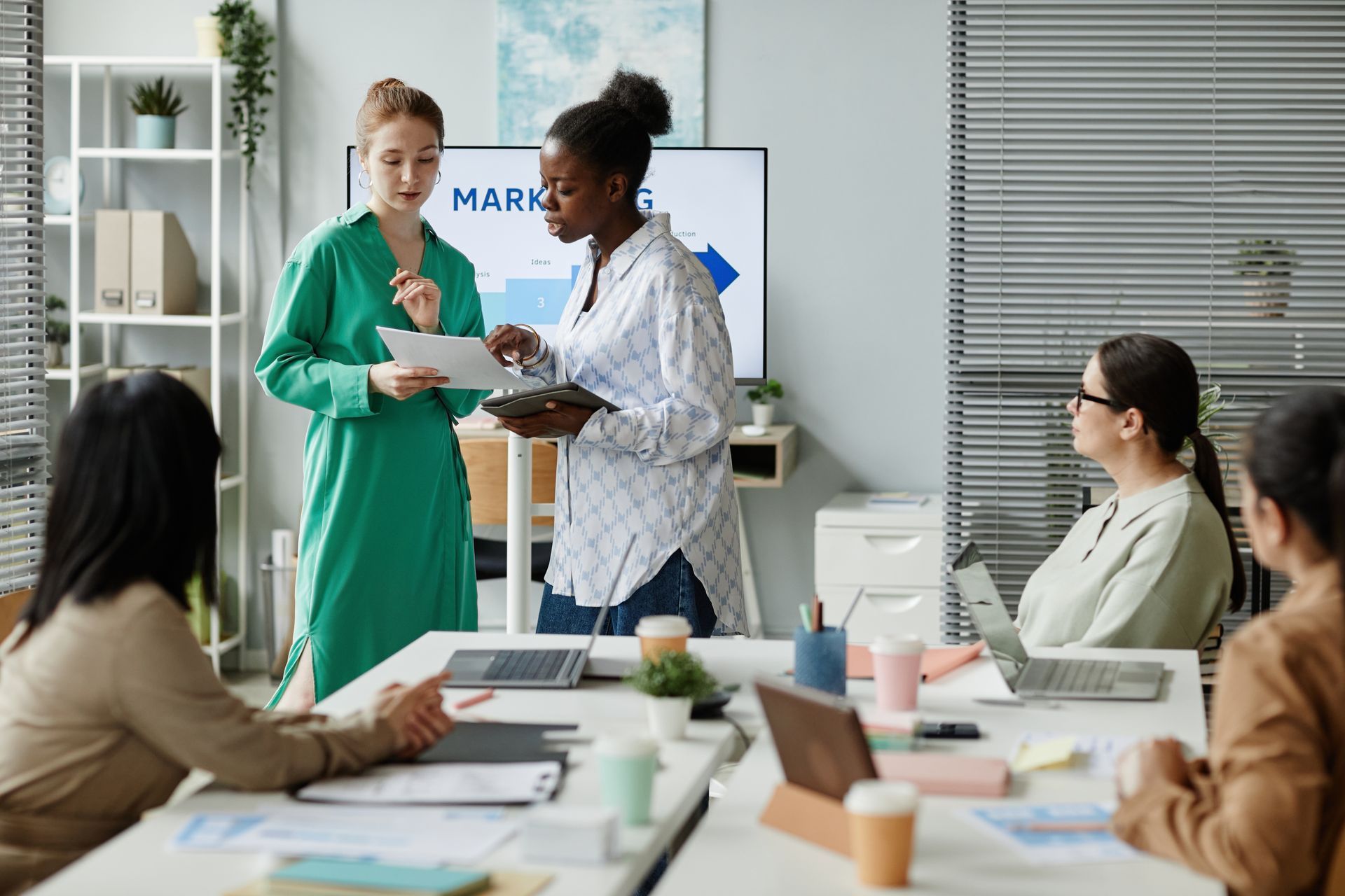 Office meeting: Women discussing marketing data.