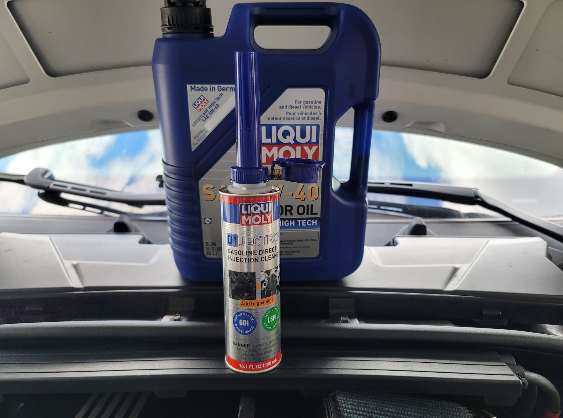 A can of liqui moly oil is sitting on the hood of a car.