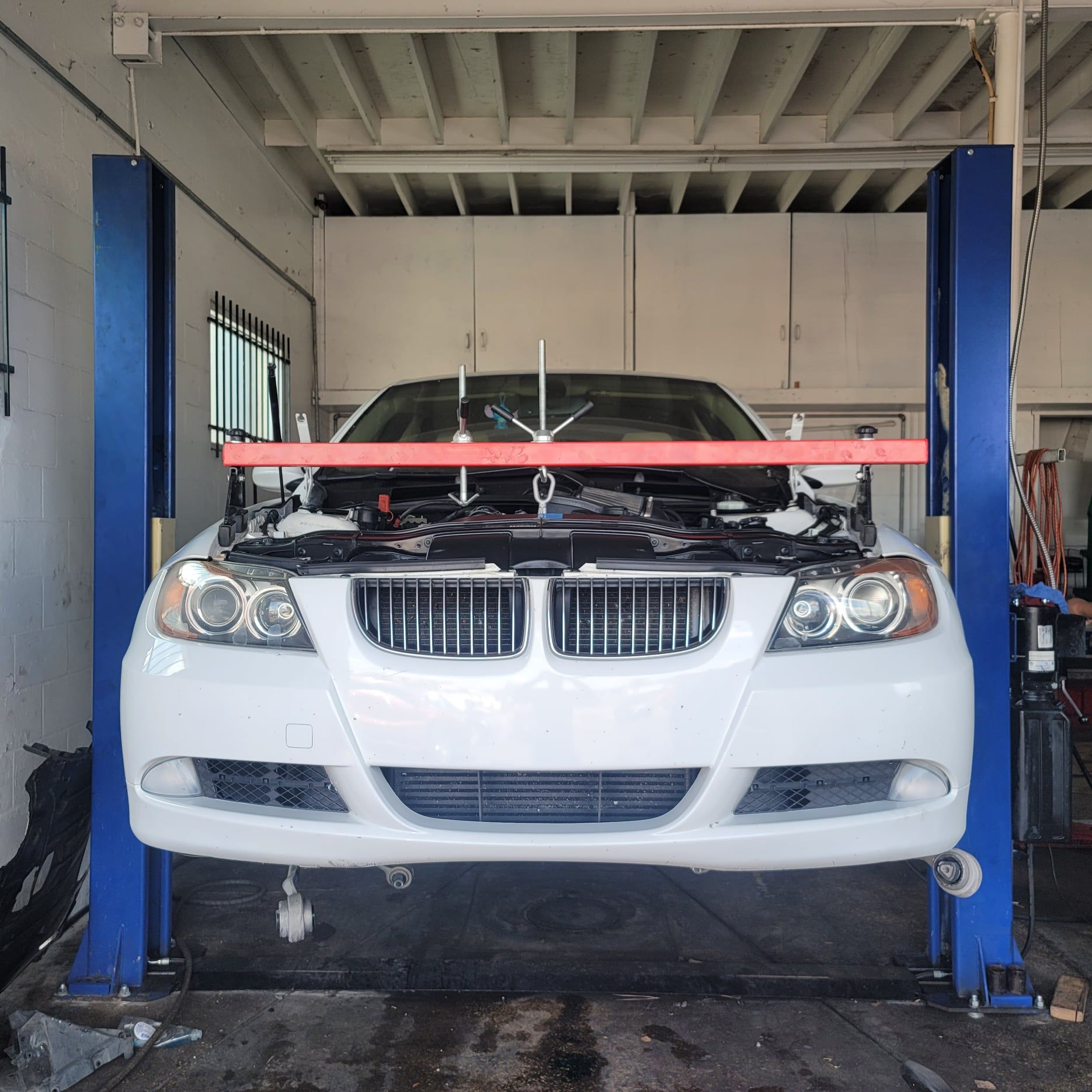 A white car is on a lift in a garage