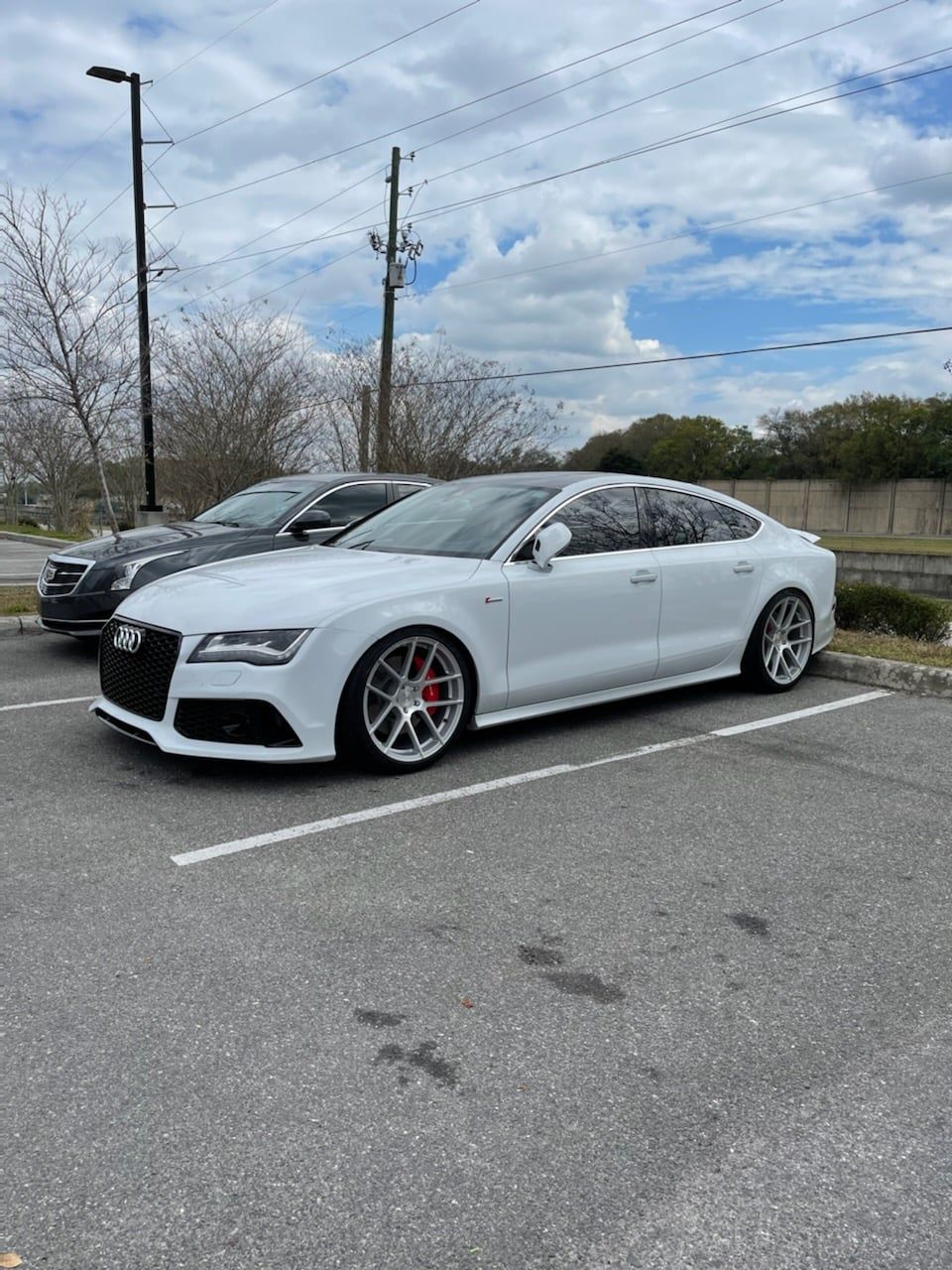 A white audi a7 is parked in a parking lot next to a black car.