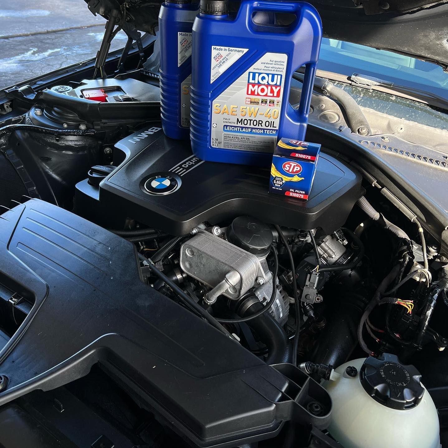 A bottle of liqui moly motor oil sits on top of a car engine