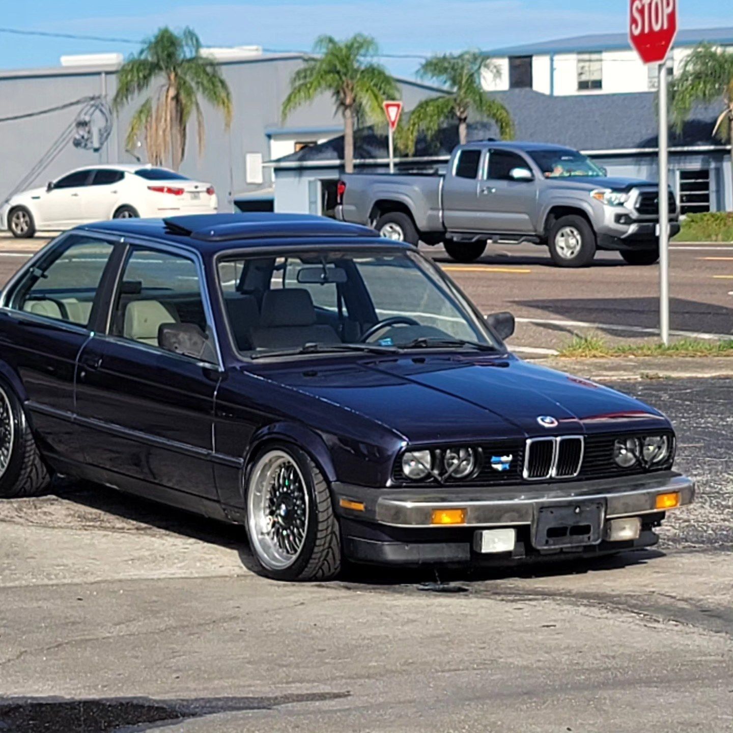 A black car is parked in front of a stop sign