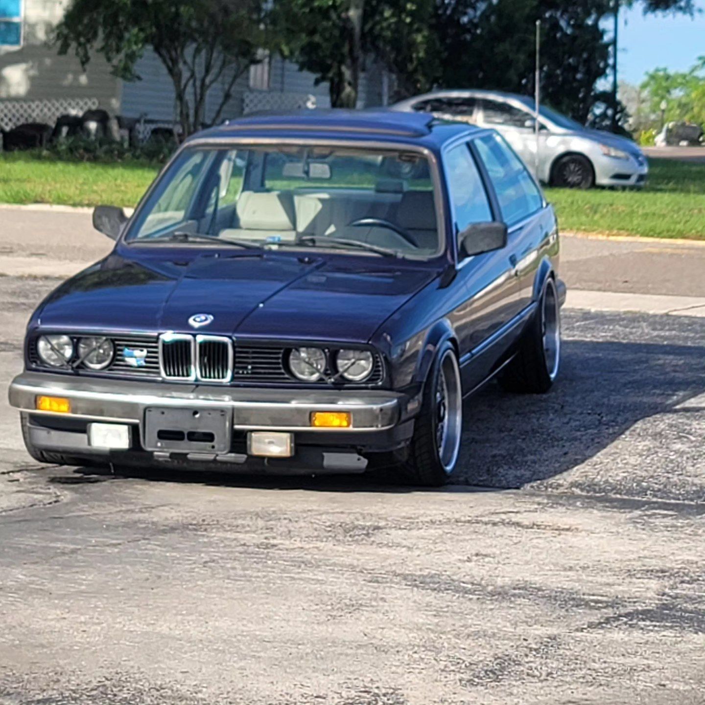 A blue bmw is parked in a parking lot