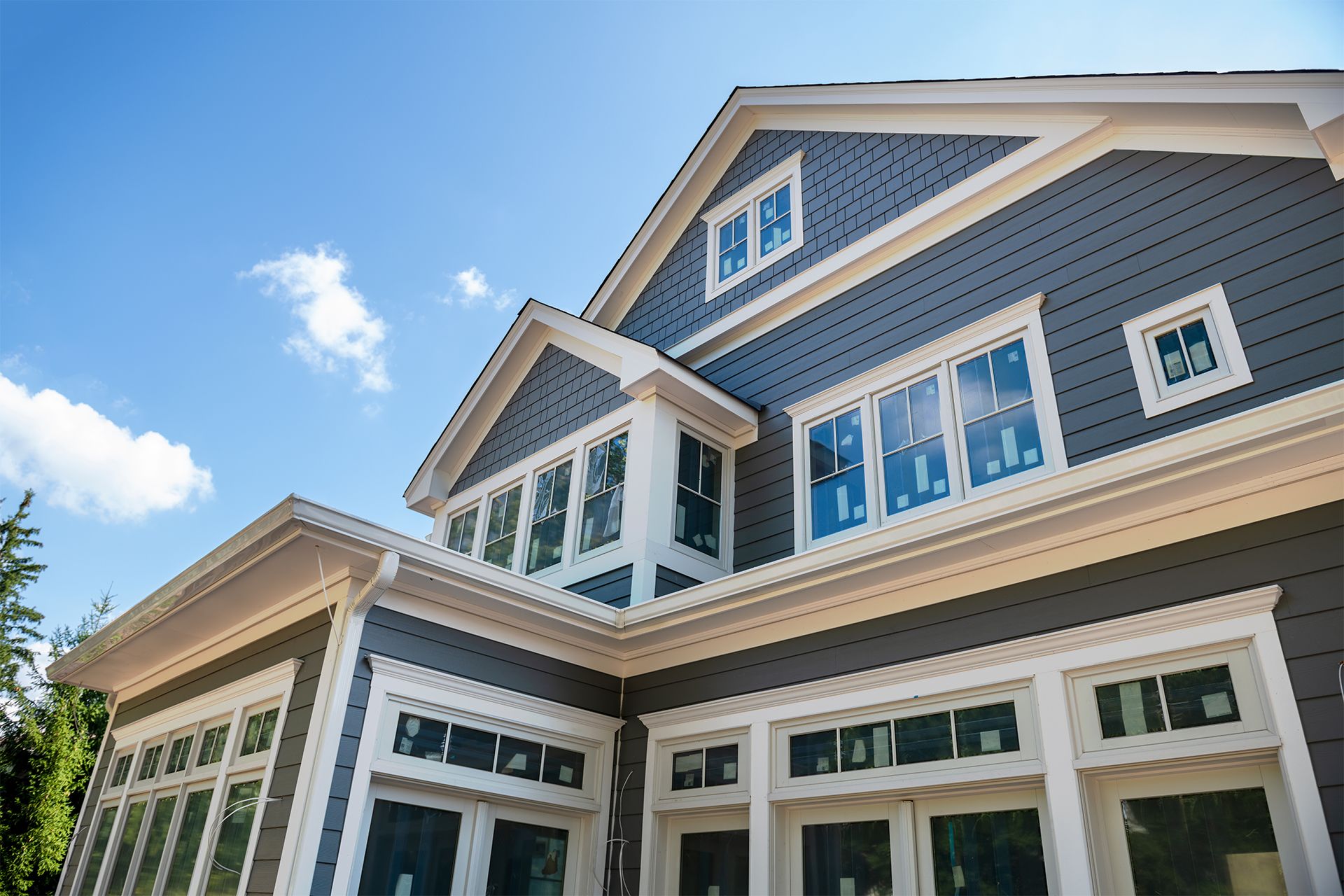 Gray house exterior with white trim against a blue sky.
