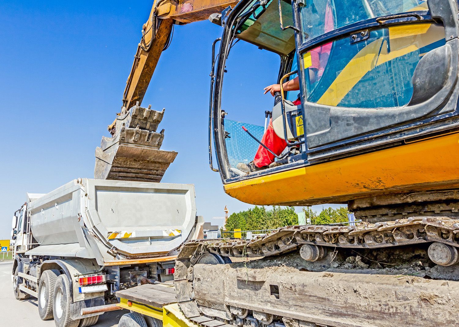 Excavator loading a dump truck with dirt at a construction site.