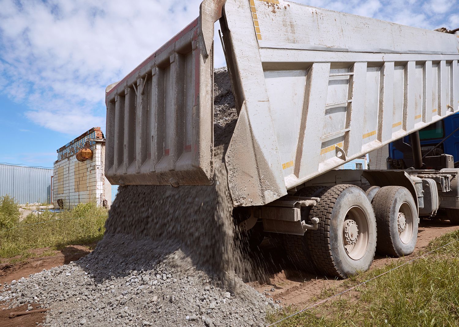 Dump truck unloading gravel onto a path.