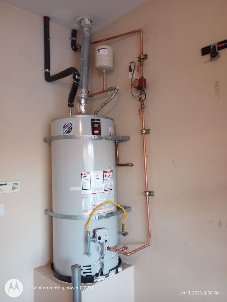 Water heater with copper pipes, vent, and expansion tank in a corner.
