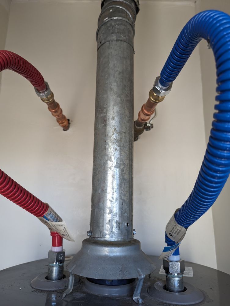 Water heater with red and blue flexible hoses connected to the top and bottom.