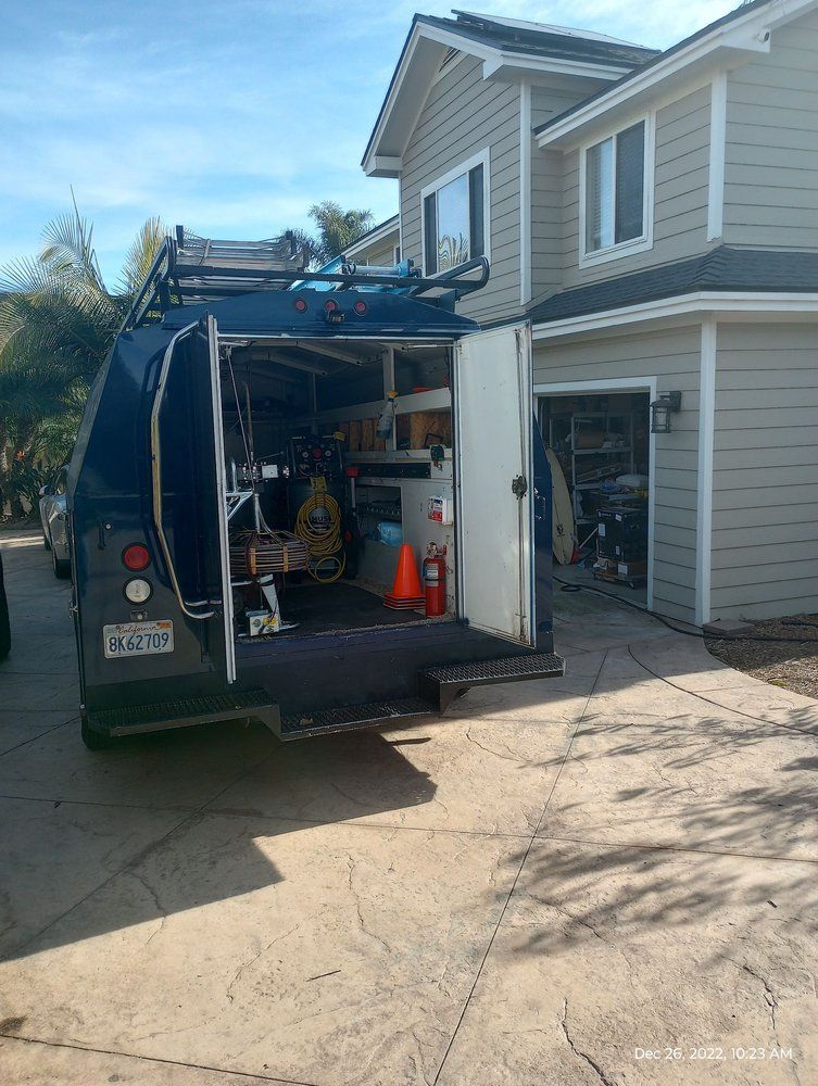 Service truck parked on a driveway in front of a house, door open revealing tools and equipment.