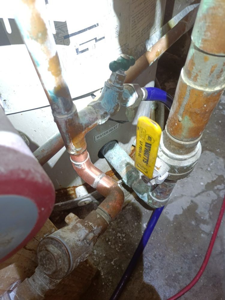Copper pipes and valves with a yellow handled shut-off valve, indoors.
