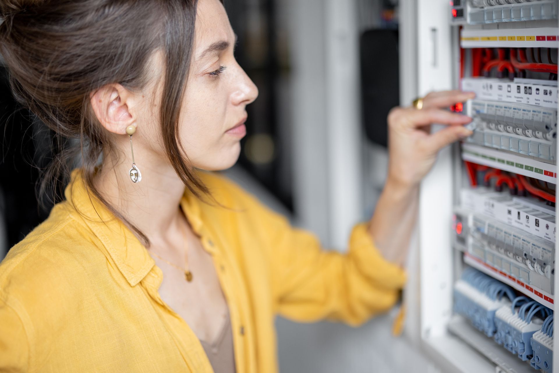 Woman checking a circuit breaker.