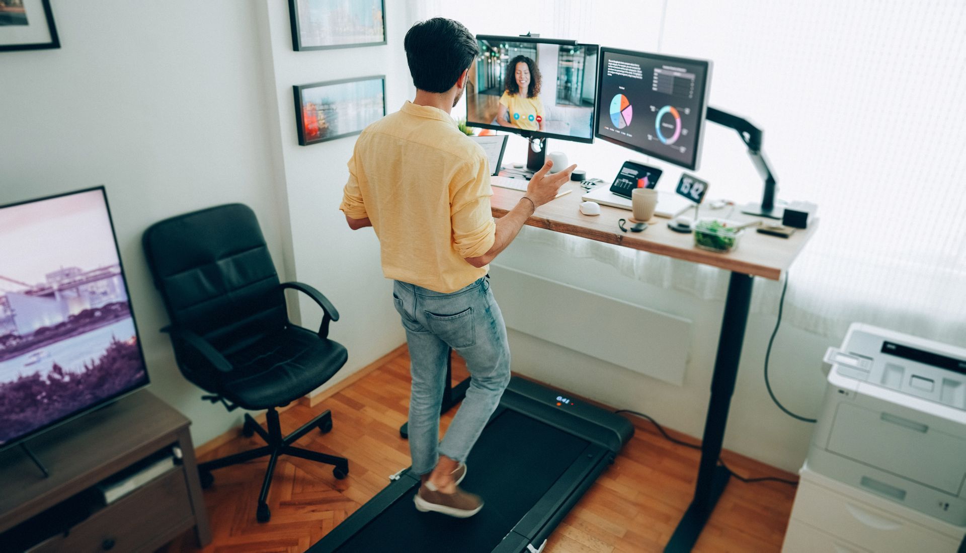 Man at standing desk home office talking on business video call.