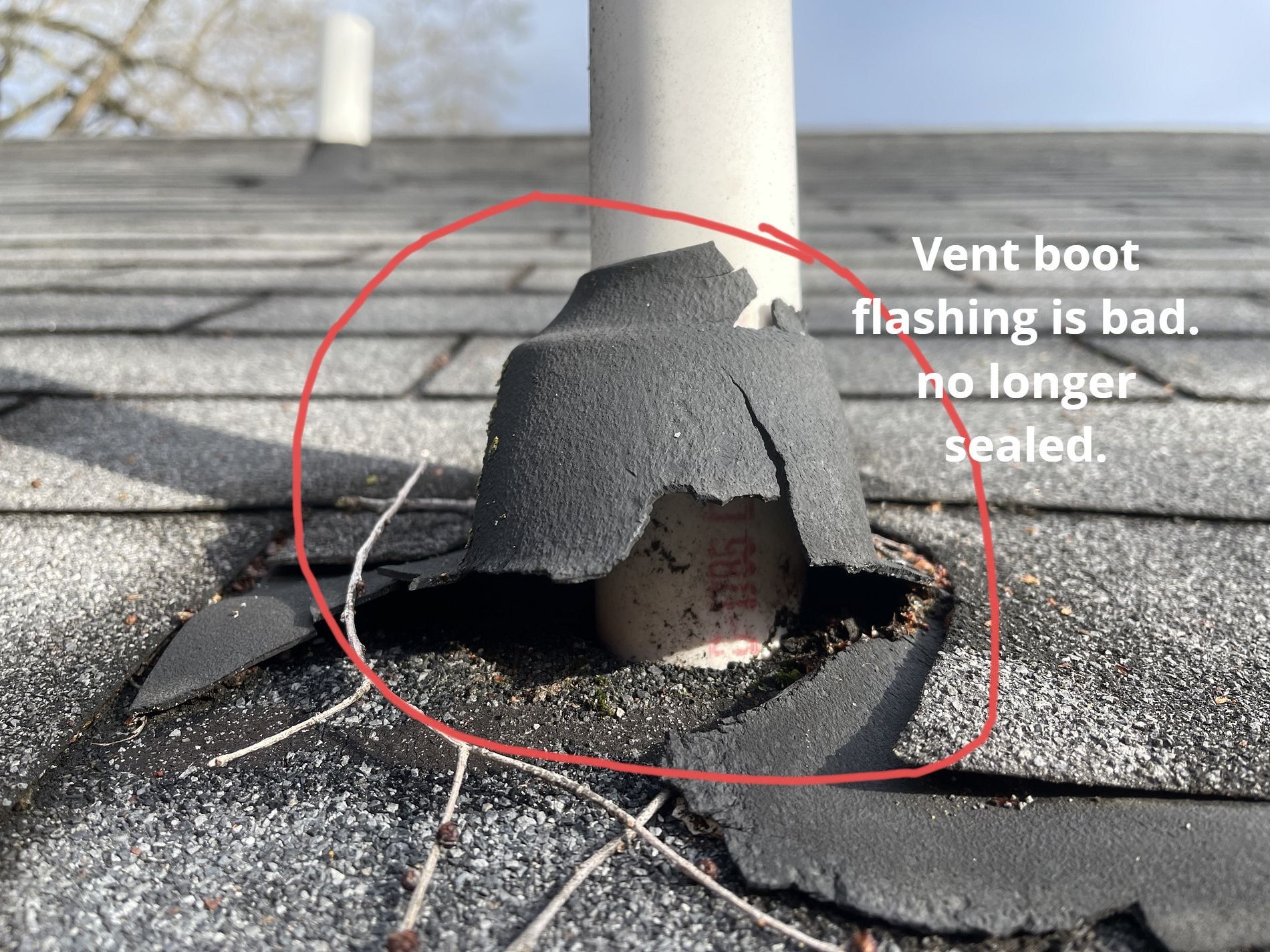 A damaged, cracked black rubber plumbing vent boot on a gray shingled roof, showing a loss of seal around the pipe.
