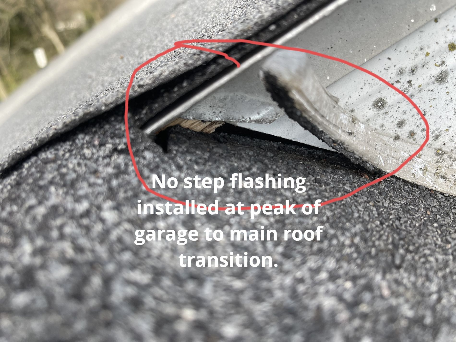 A close-up of a roof transition showing missing step flashing where the garage roof meets the main wall, circled in red.