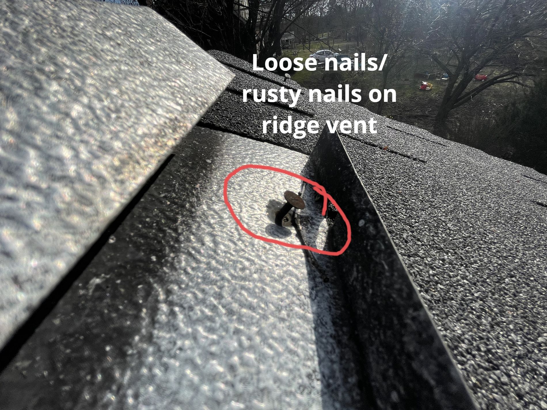 A close-up view of a roof ridge vent showing a loose, rusted nail circled in red, highlighting maintenance issues.