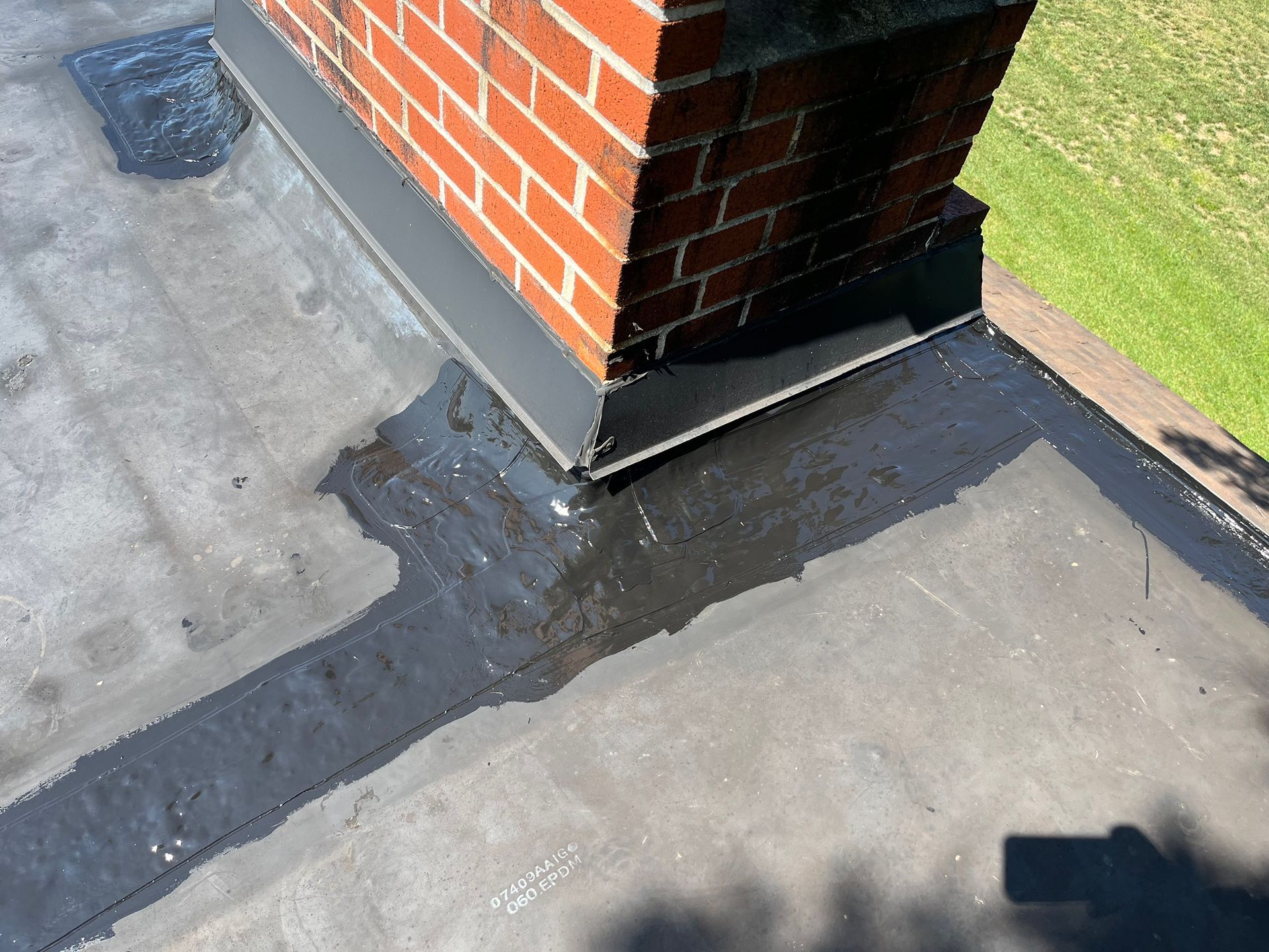 A worker uses a propane torch to install rolled bitumen roofing material on a flat roof.