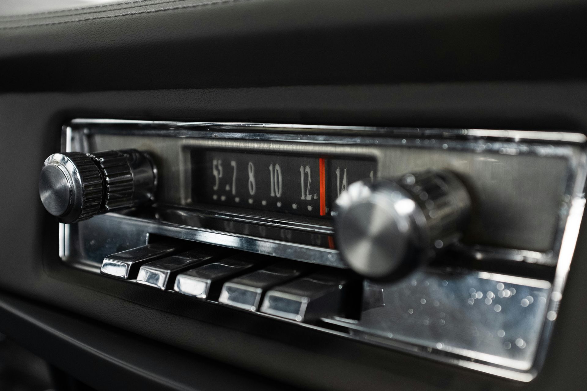 Car radio with dials and buttons; chrome finish, black interior.