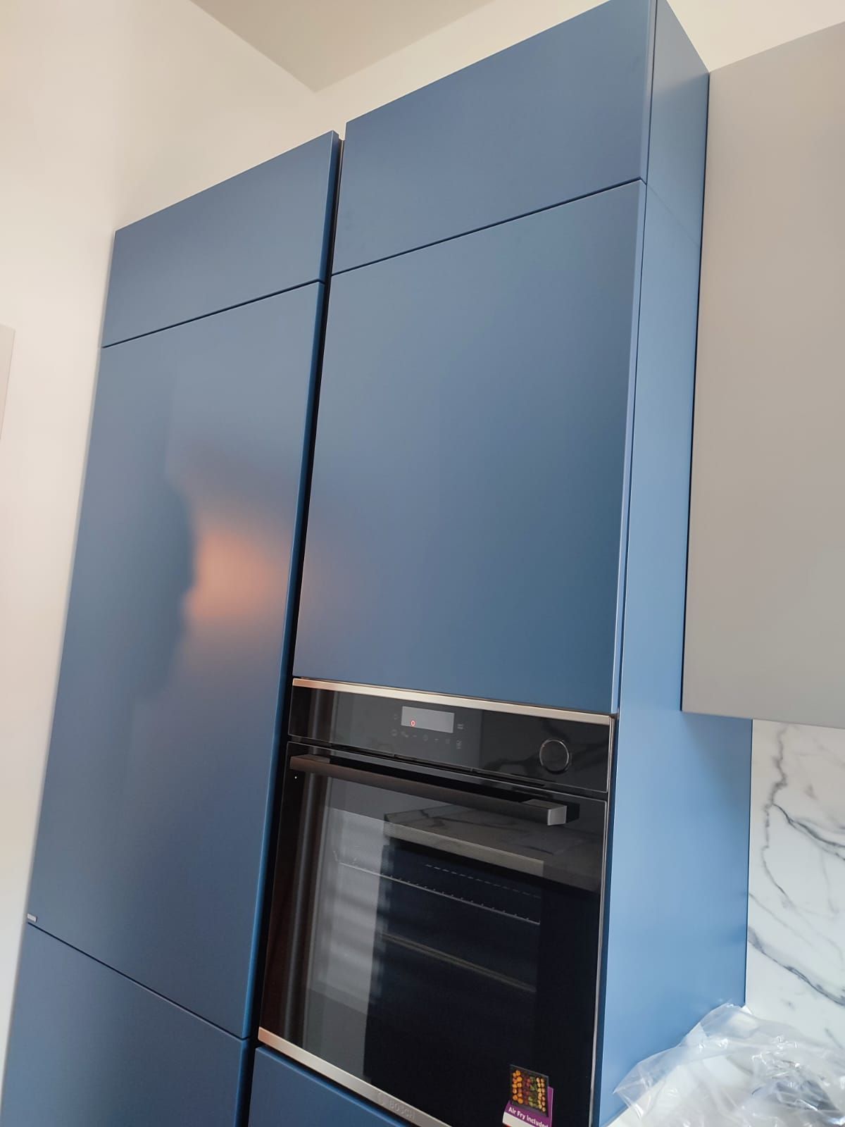 Mobili da cucina alti blu con forno incorporato.