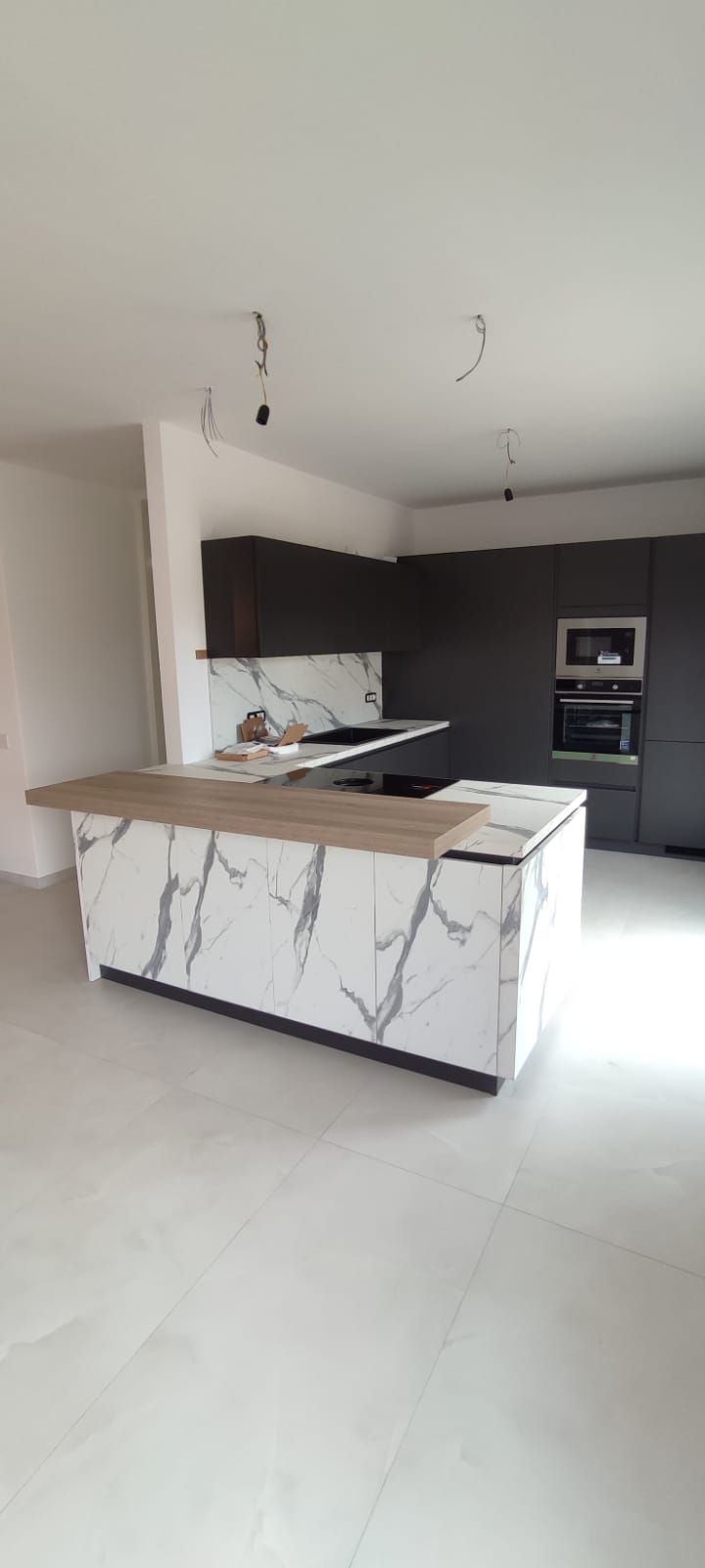 Cucina moderna con isola in marmo bianco e mobili scuri.