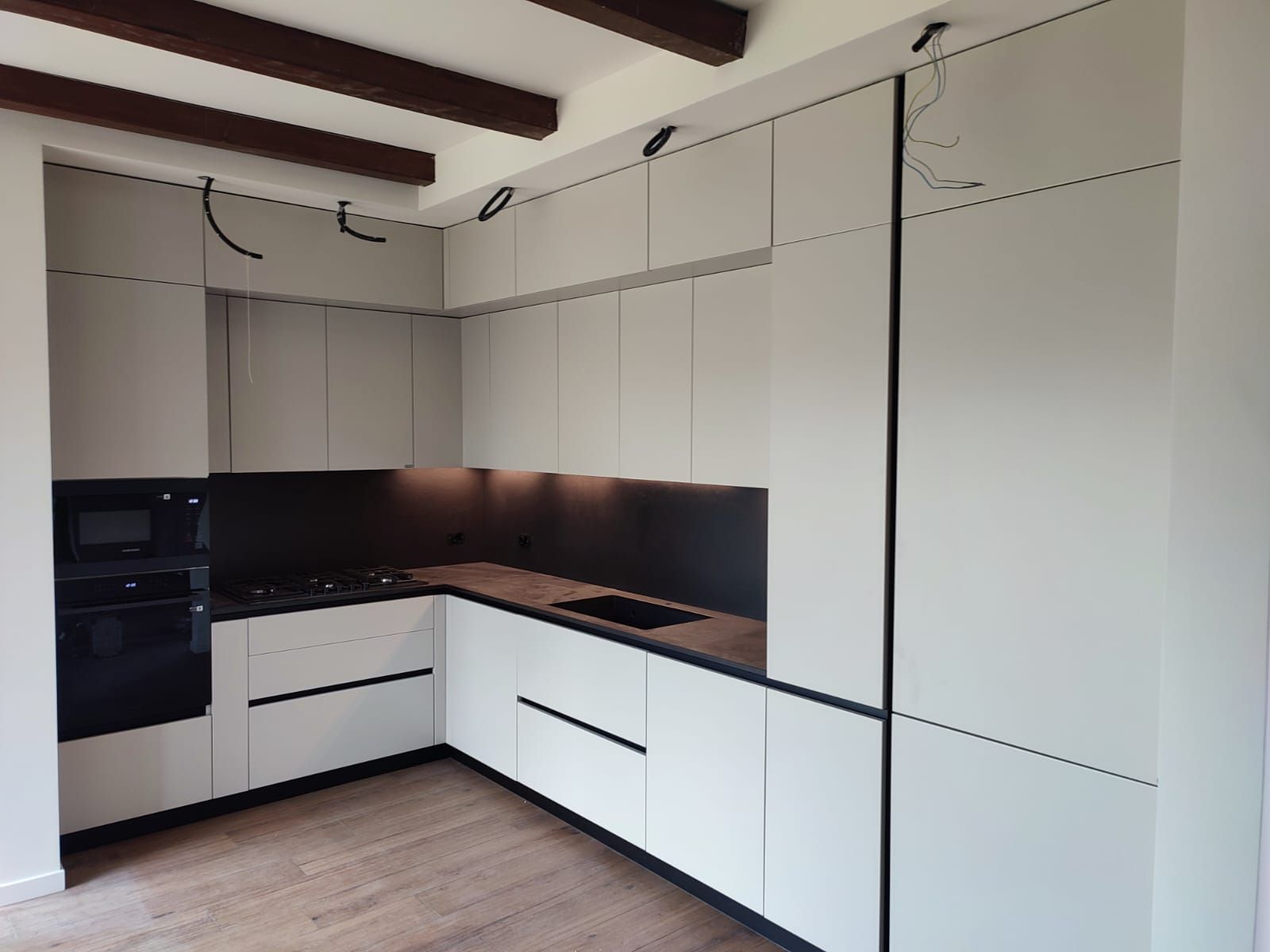 Moderni mobili da cucina grigio chiaro con dettagli neri e ripiani in legno.