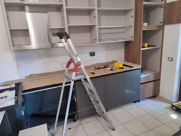 Installazione dei mobili della cucina, con l'utilizzo di una scala a pioli.