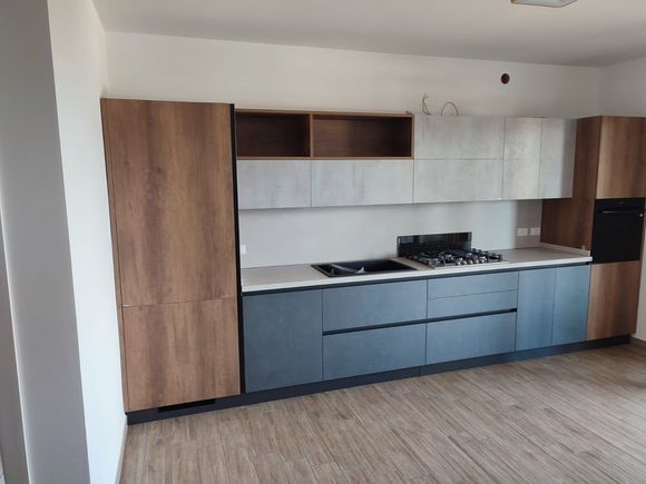 Cucina moderna con mobili in legno e grigi, piano cottura e forno.