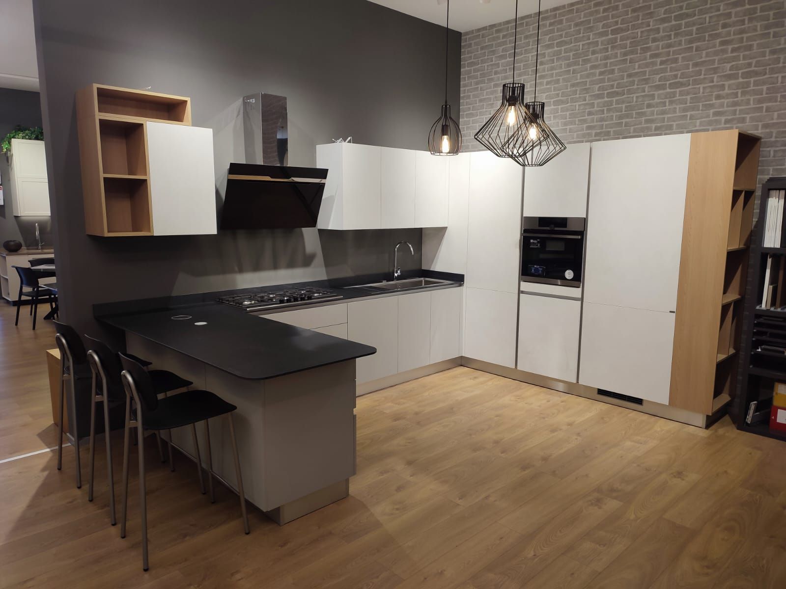 Cucina moderna con mobili bianchi, ripiani neri e un bancone per la colazione.