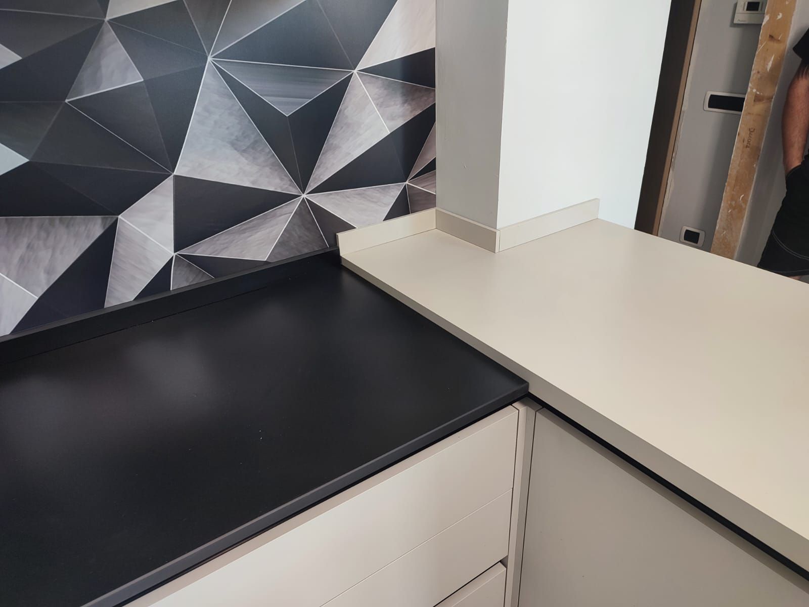 Piano di lavoro della cucina con paraschizzi geometrico e piano di lavoro in bianco e nero a contrasto.