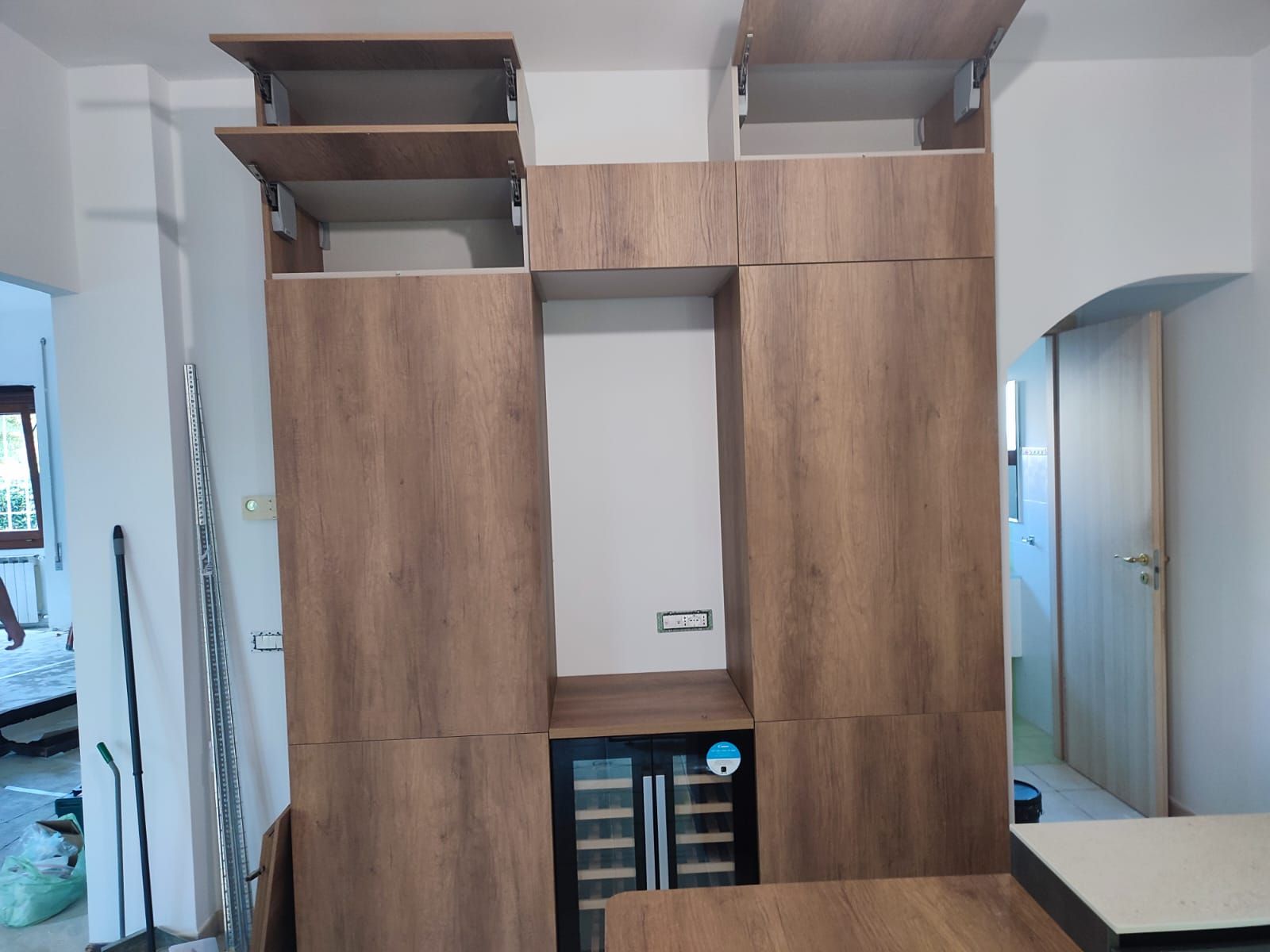 Mobili da cucina in legno con installato un refrigeratore per vino, in fase di costruzione.