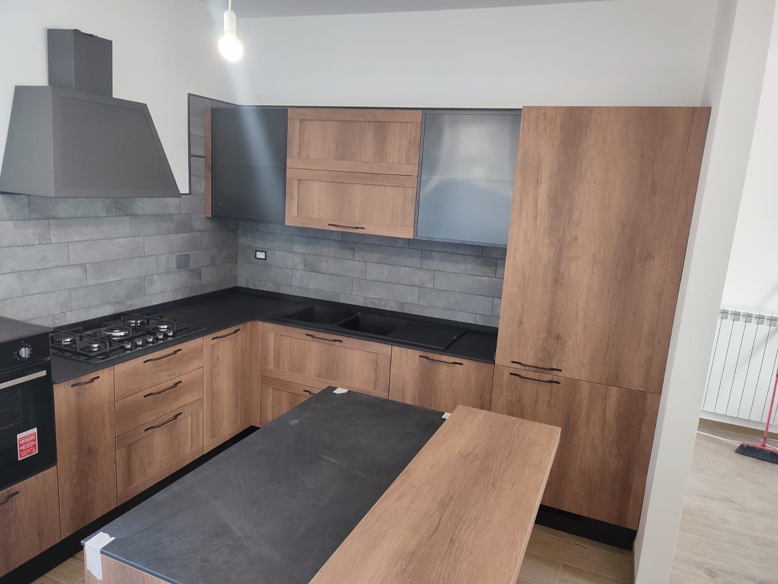 Cucina moderna con mobili in legno, ripiani scuri e isola centrale.