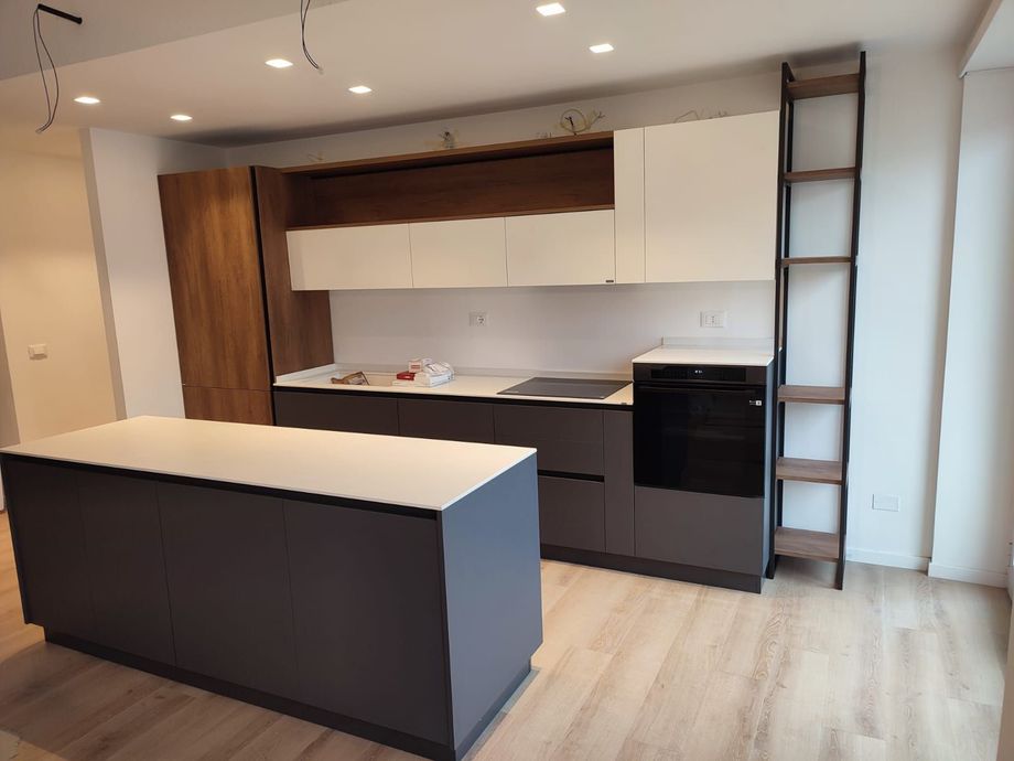 Cucina moderna con mobili grigi e bianchi, dettagli in legno e una grande isola.