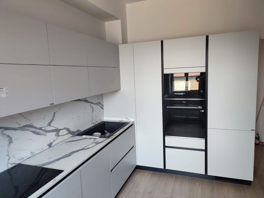 Moderna cucina bianca con paraschizzi in marmo e forno incorporato.