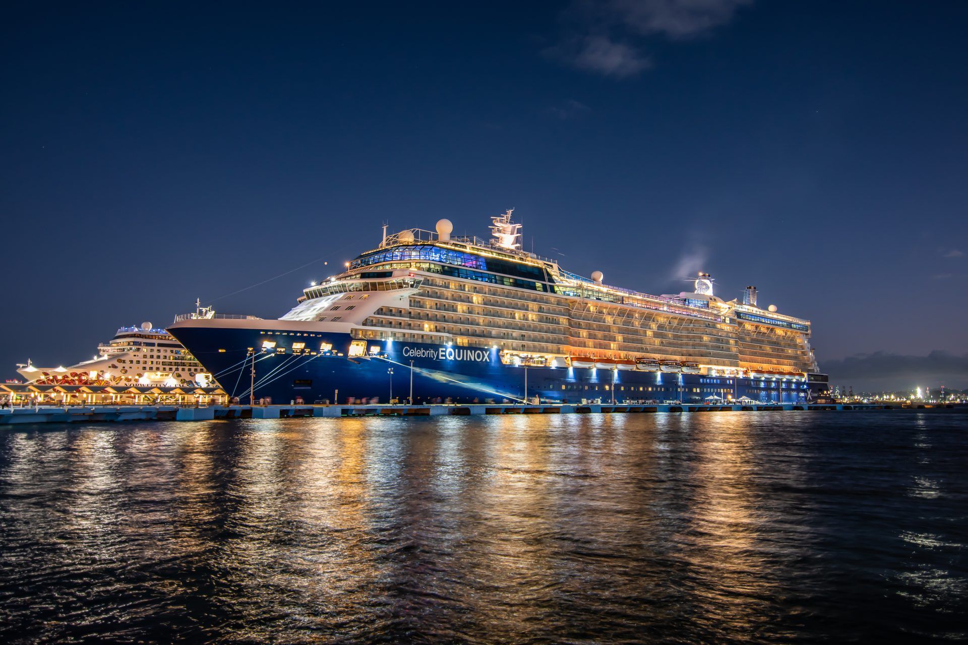 A large cruise ship is docked in a harbor at night.
