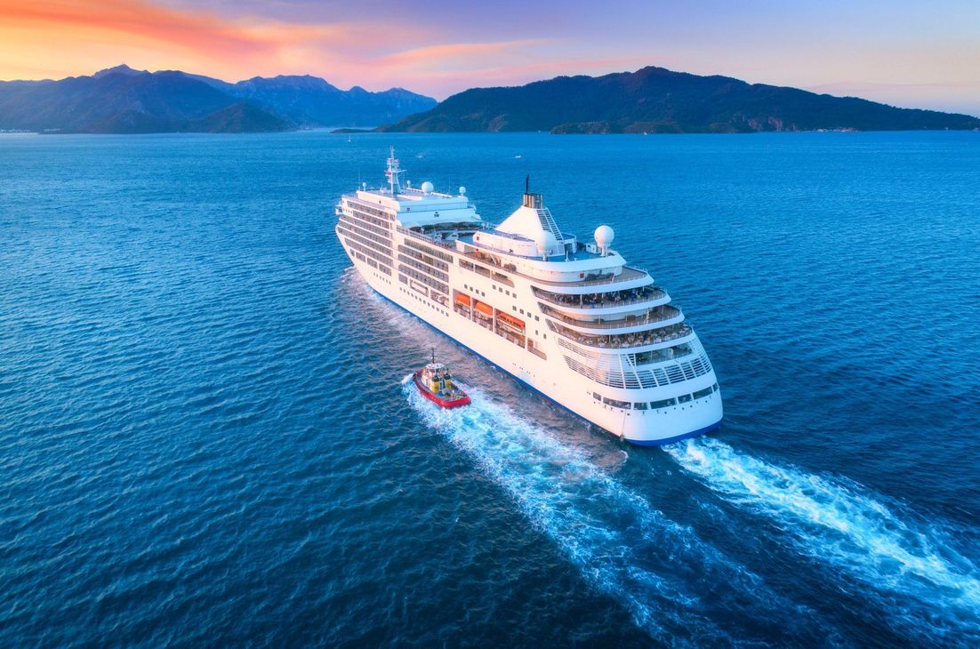 An aerial view of a cruise ship and a small boat in the ocean.