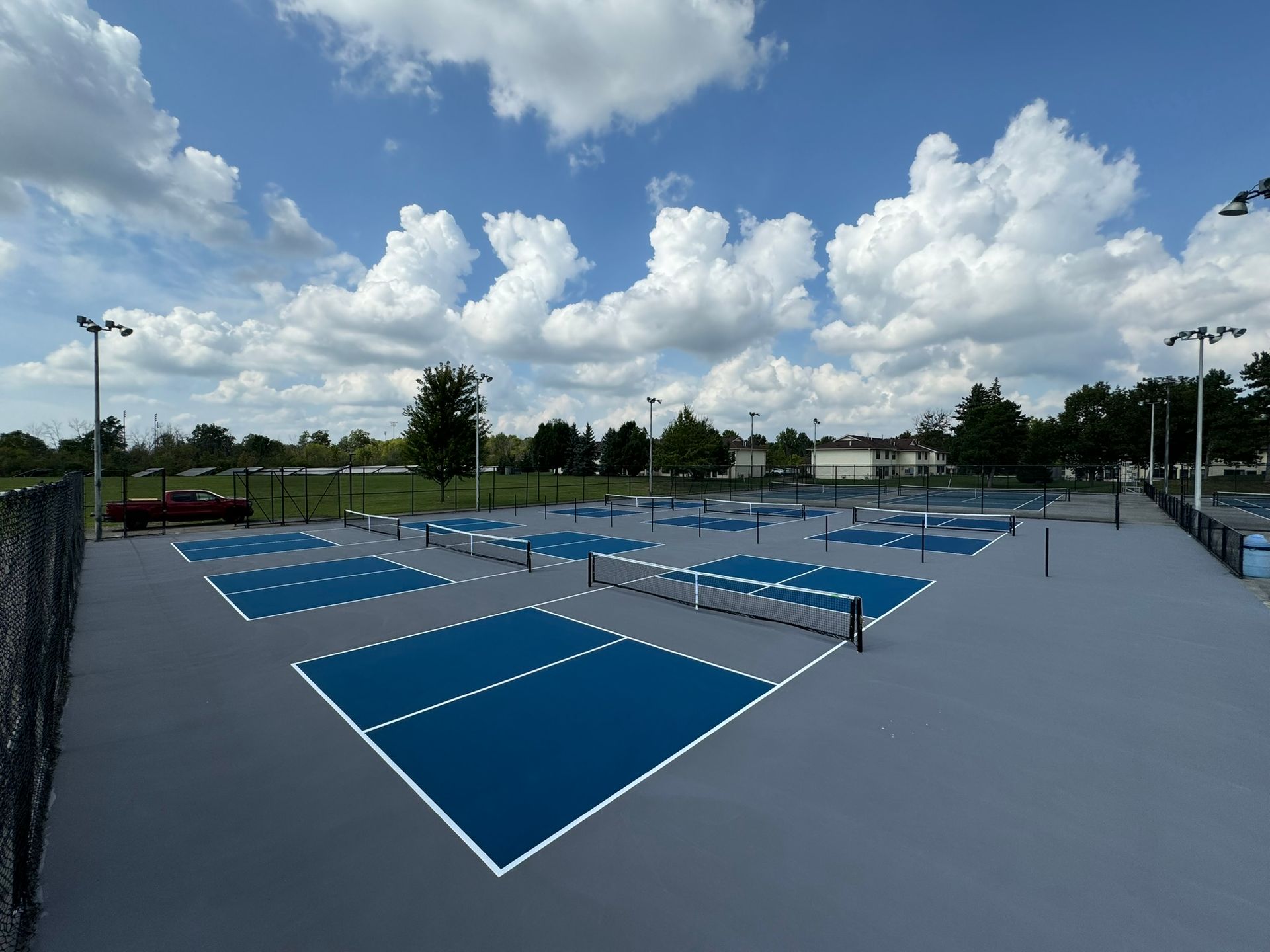A tennis court with blue courts and white lines on a cloudy day.