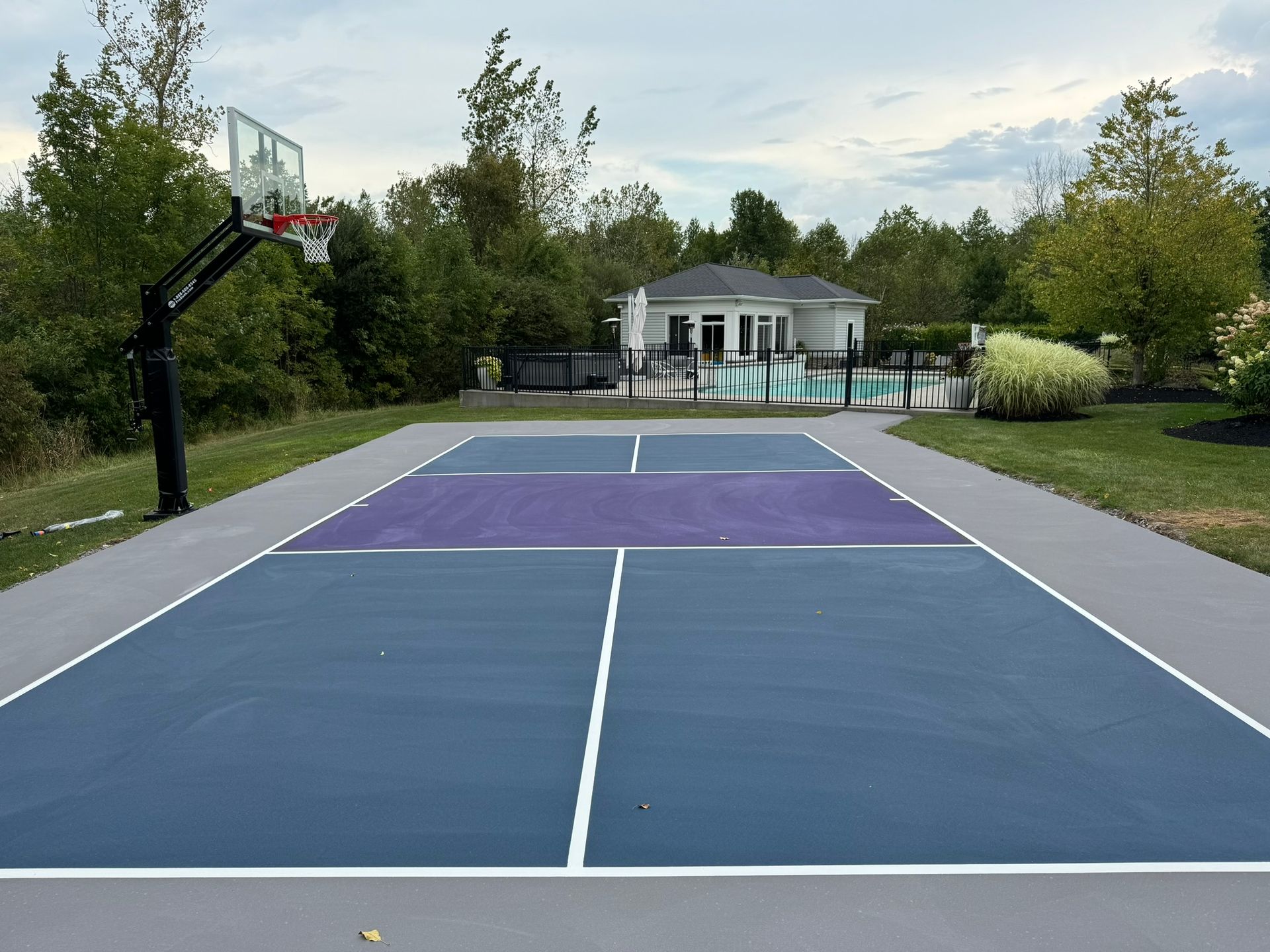 A blue and purple basketball court with a house in the background