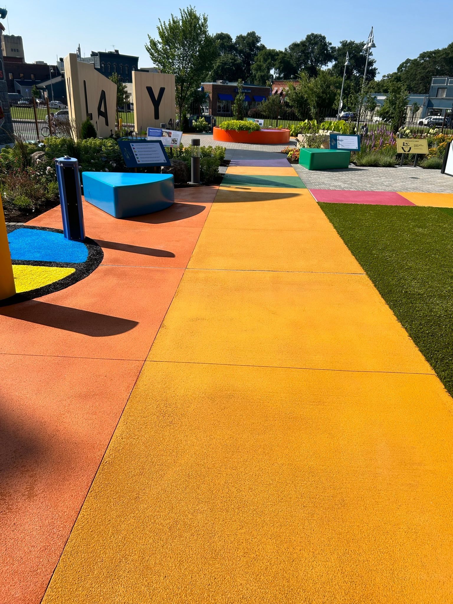 A colorful walkway in a park with a blue bench in the middle.