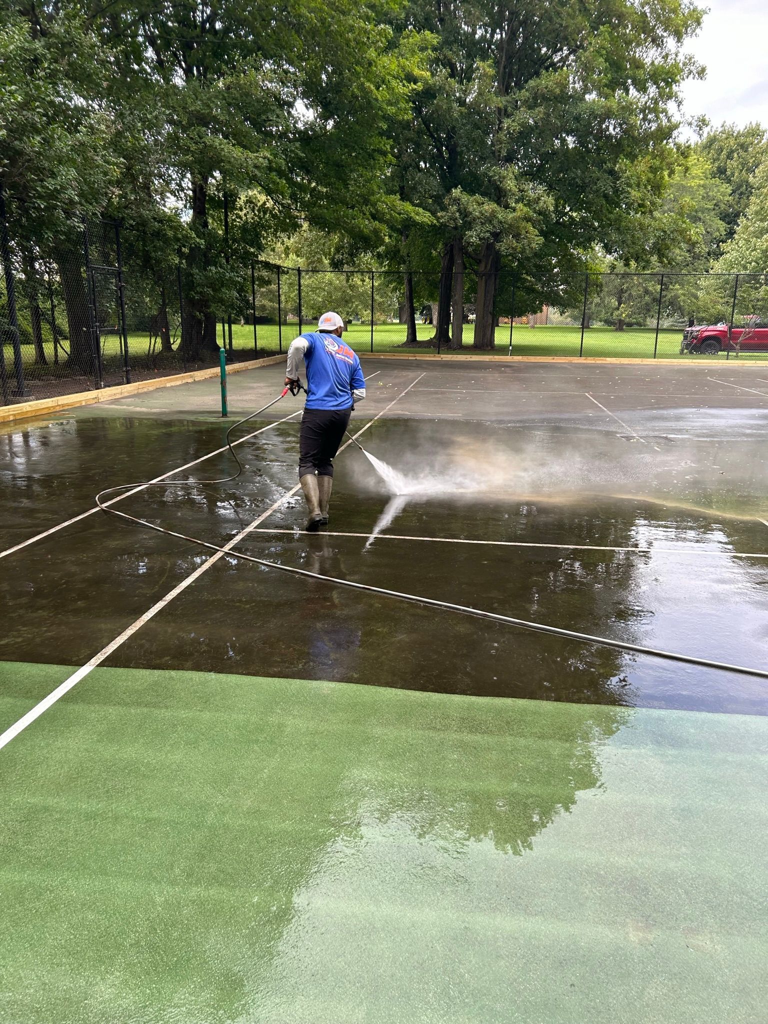 A man is cleaning a tennis court with a pressure washer.